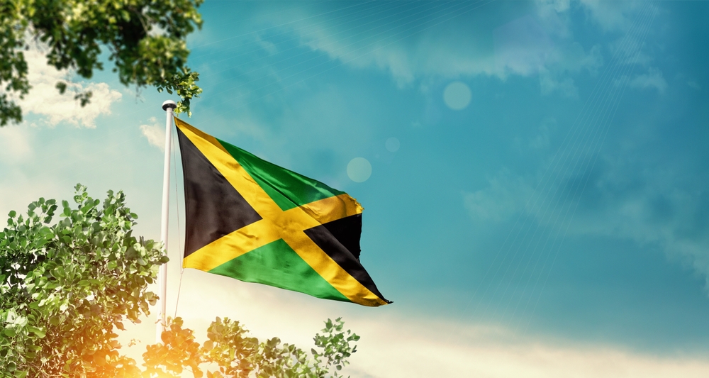 Jamaica,National,Flag,Waving,In,The,Sky,Behind,The,Tree.